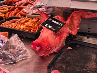 Fresh pork selection in butcher shop featuring pig head display? A pig's head on a market counter...