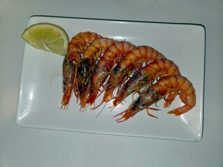 Fresh cooked shrimps with lemon slice on rectangular plate. Mediterranean diet. Spanish tapas