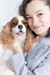 a woman holds a King Charles spaniel in her arms