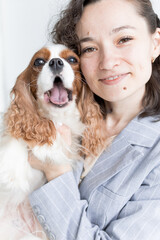 a woman holds a King Charles spaniel in her arms
