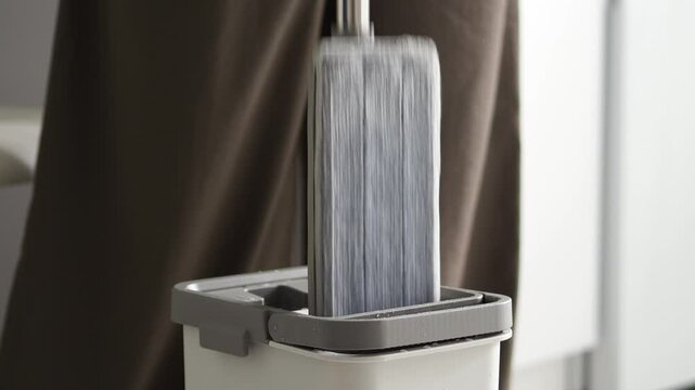 The innovative cleaning tool is a mop handle placed in a grey bucket, which highlights the modern design and practicality for efficient cleaning and home maintenance.