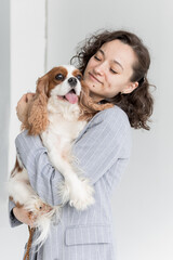 a woman holds a King Charles spaniel in her arms
