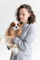 a woman holds a King Charles spaniel in her arms