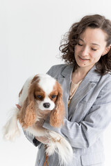 a woman holds a King Charles spaniel in her arms