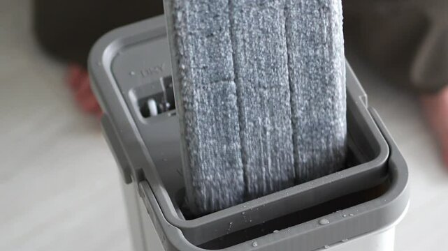 The innovative cleaning tool is a mop handle placed in a grey bucket, which highlights the modern design and practicality for efficient cleaning and home maintenance.