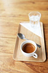 Hot coffee and glass of ice cold water on wooden tray on wooden table