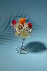 Colorful flowers in ice cubes in the glass on pastel blue background. Sunny day concept.