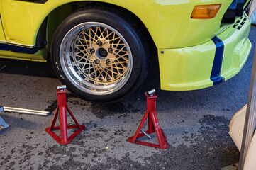 Detailed view of red jack stands used to support a raised race car for wheel changes and repairs,...