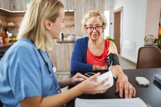 Caring nurse checks blood pressure of elderly woman in home setting