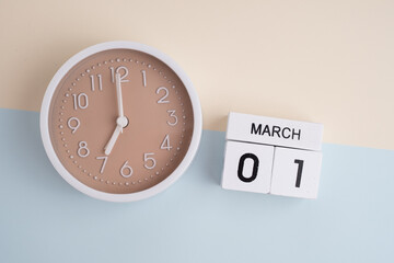 March 1st.Wooden calendar with the date March 1 and a clock on a colored background with copy...