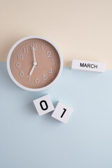 March 1st.Wooden calendar with the date March 1 and a clock on a colored background with copy...