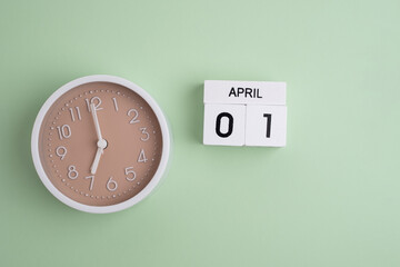 April 1st.Wooden calendar with the date April 1 and a clock on a colored background with copy...