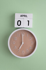 April 1st.Wooden calendar with the date April 1 and a clock on a colored background with copy...