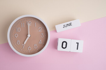 June 1st. Wooden calendar with the date June 1 and a clock on a colored background with copy space....