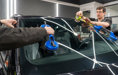 Automobile special workers replacing windscreen or windshield of a car in auto service station...