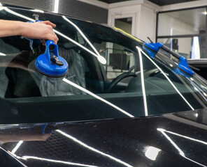 Automobile special workers replacing windscreen or windshield of a car in auto service station...