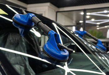 Automobile special workers replacing windscreen or windshield of a car in auto service station...