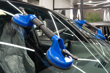Automobile special workers replacing windscreen or windshield of a car in auto service station...