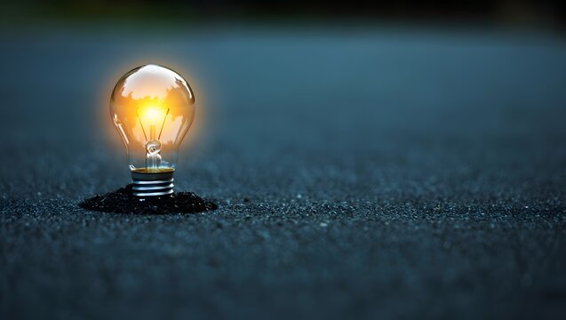 Illuminated light bulb on dark surface symbolizing idea innovation and creativity