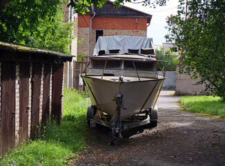 Small Boat Covered on a Trailer Parked in a Residential Backyard or Driveway