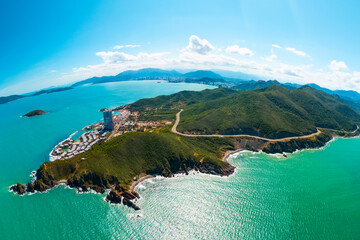 Aerial view bright blue waters meet lush green hills in Nha Trang, Vietnam. Visitors can enjoy the...