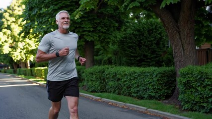 Mature man is jogging in the street. Elderly male running outside. Runner.Sport and healthy lifestyle concept. Aging youthfully. People and sport concept - Powered by Adobe