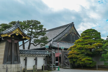 An elegant white turret and a long defensive wall rise above a massive stone base at Nijo Castle, showcasing the clean lines and formidable presence of feudal architecture in Kyoto, Japan.