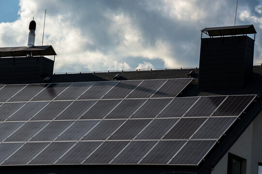 Rooftop solar panels catch sunlight under a partly cloudy sky, demonstrating sustainable energy use in modern homes