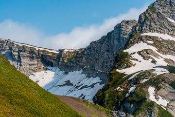 Gorgeous landscape in the mountains with snow-capped hills and clouds over the peaks of the mountains, Sochi, Krasnaya Polyana