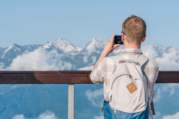 A man takes pictures and enjoys the view of the picturesque landscape of mountain slopes with...