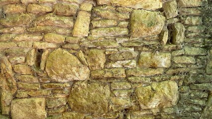 Ancient wall stone masonry in fence around the house, large and small stones.