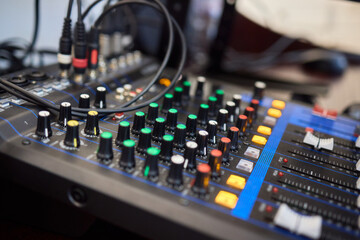 Closeup image of a hand mixing sounds on a control board, showcasing an audio technicians work