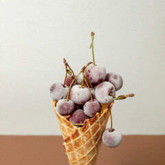 Frozen cherries in ice cream cone, on white and brown background. Still life, Flat lay