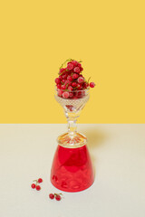 Red currants in a glass on a yellow background. Vibrant food photography. Still life