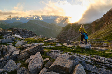 Mother and son embracing at sunset in the mountains watching the scenery during a hike.