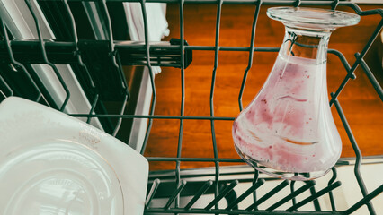 Dirty glass carafe and plates inside an open dishwasher