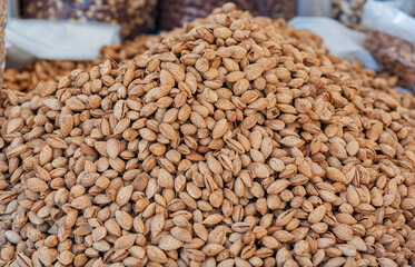A bountiful pile of raw almonds in their shells, captured up close at an outdoor market stall with...