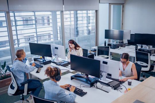 In a modern office, a diverse team collaborates effectively towards shared goals using technology