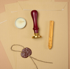 A wax seal kit including wax sticks, candles, stamp and sealed scroll placed on a neutral background