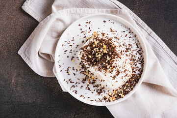 Close up of ice cream sprinkled with chocolate chips and nuts on a plate on the table top view
