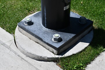 Large baseplate mounted on cement for light pole.