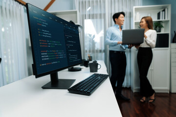 Running on coding programming intelligence system on computer screen with blurry IT developers standing with laptop at corner modern office, talking online software development information. Infobahn.