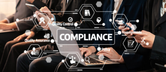 A group of professionals engaged in a business meeting focused on compliance and quality assurance, showcasing modern technology in a corporate environment. Amity