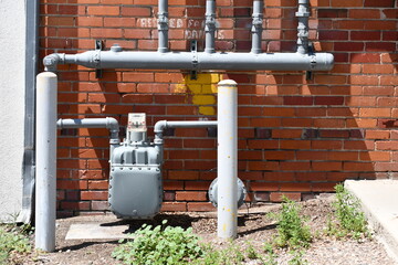 Gas meter with multiple valves on manifold. Brick building in alleyway.