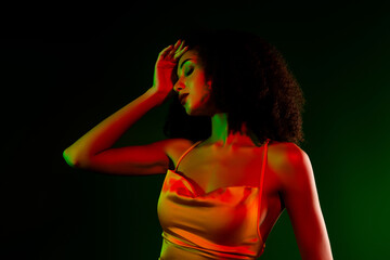 Stylish African American woman in elegant attire, illuminated with creative red and green lighting