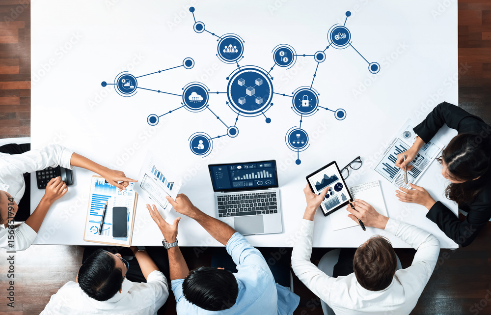 Poster A vibrant business meeting showcasing technology and data visualization on a sleek table. Professionals engage with laptops and tablets, sharing insights and strategies in a modern workspace. Amity