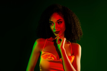 Elegant young woman in a vibrant lighting setup posing confidently in a stunning yellow cocktail...