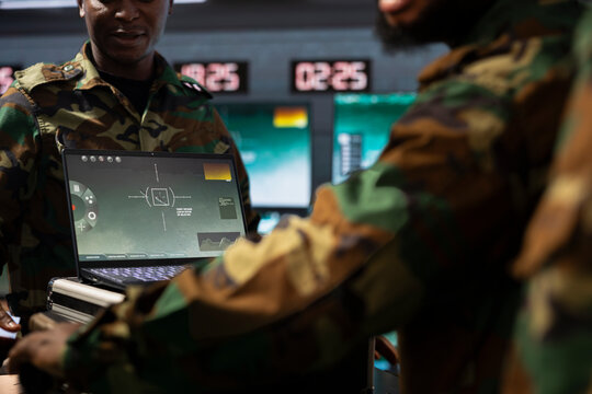 Military officers operating aerial systems on laptop device to support reconnaissance and target identification. Army specialists monitoring counterinsurgency operations with notebook software