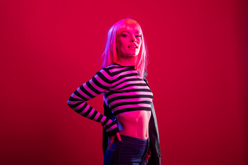 Female model with striped outfit and pink wig stands in calm yet assertive pose against isolated...