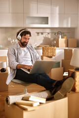 A man sits in a chair with headphones on, focused on his laptop while surrounded by numerous...